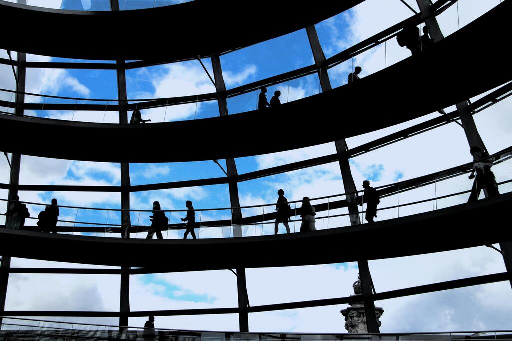 Silhouettes of people walking inside a glass dome